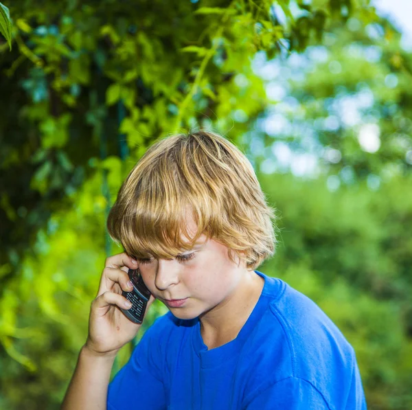 Ung pojke talar i en mobiltelefon. — Stockfoto