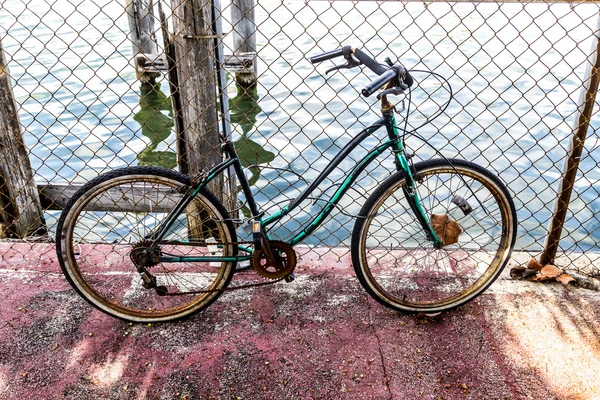 Velha bicicleta podre em uma cerca enferrujada — Fotografia de Stock