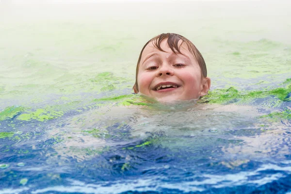 Garçon nage dans une piscine extérieure chaude — Photo