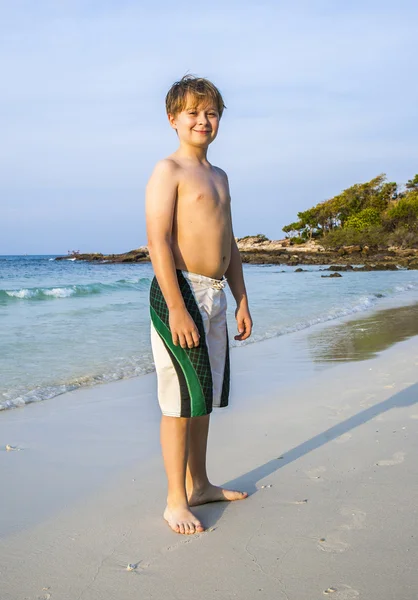Szczęśliwy s młody chłopak walkes wzdłuż przepięknej, piaszczystej plaży — Zdjęcie stockowe