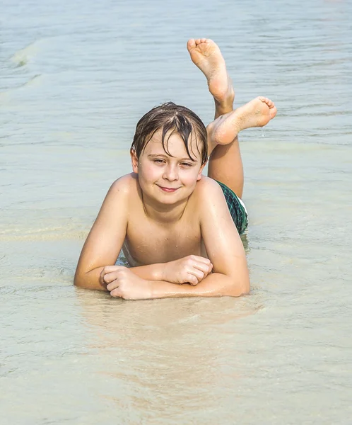 Menino está deitado na praia — Fotografia de Stock