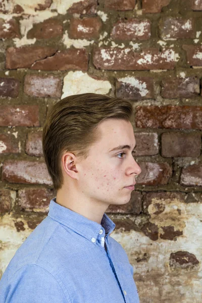 Bonito adolescente menino na frente de grungy tijolo parede — Fotografia de Stock