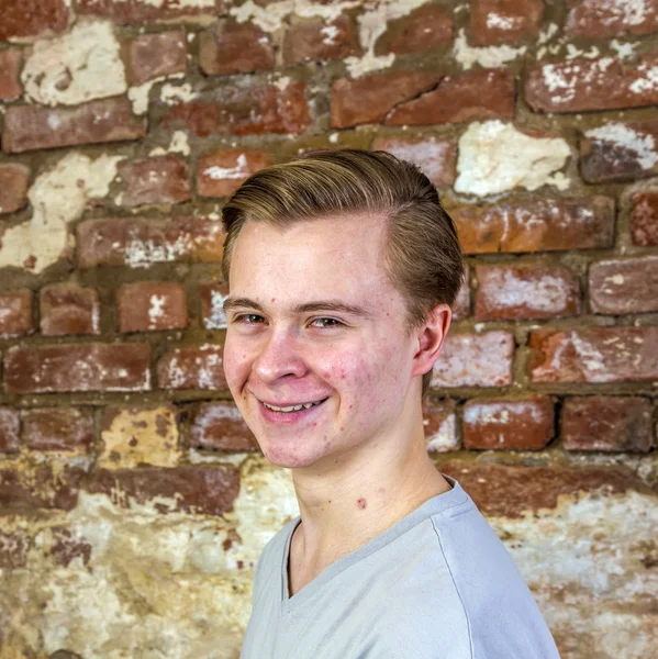 Bonito adolescente menino na frente de grungy tijolo parede — Fotografia de Stock