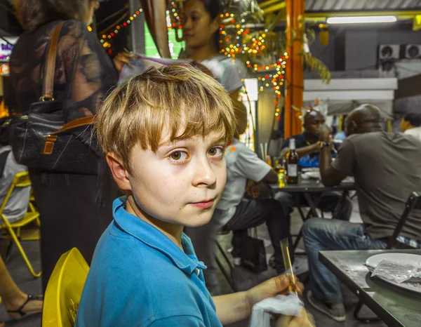 Chico disfruta comer en el mercado nocturno — Foto de Stock