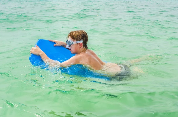 Jonge jongen geniet van paardrijden op de surfplank — Stockfoto