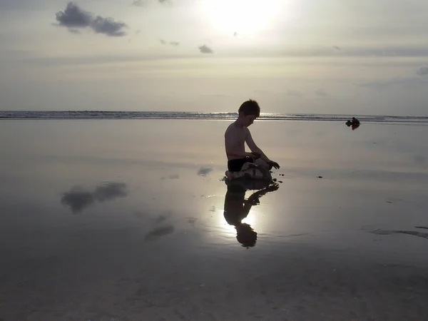 समुद्र तट पर लड़के खेलने के साथ सूर्यास्त — स्टॉक फ़ोटो, इमेज