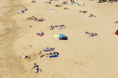 Çok sayıda turistin güneşli bir günde Papagayo kumsalın tadını çıkar