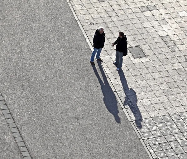 Mensen lopen in de straat met lange schaduwen — Stockfoto