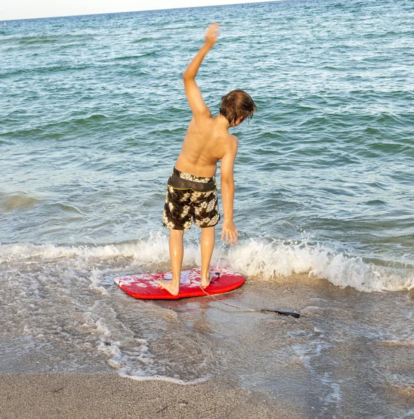 Çocuk plajda sörf öğrenir — Stok fotoğraf