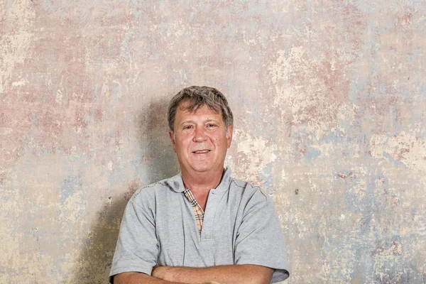 Portrait of senior man in front of grungy old wall — Stock Photo, Image