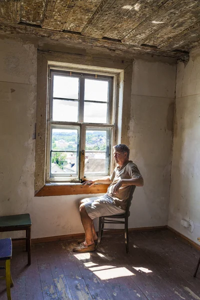 Hombre sentado en la ventana de una casa vieja — Foto de Stock