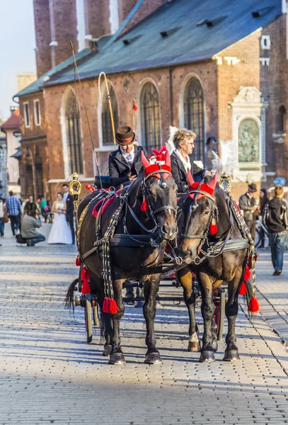 Carruajes de caballos frente a la iglesia Mariacki en la plaza principal de Kr —  Fotos de Stock