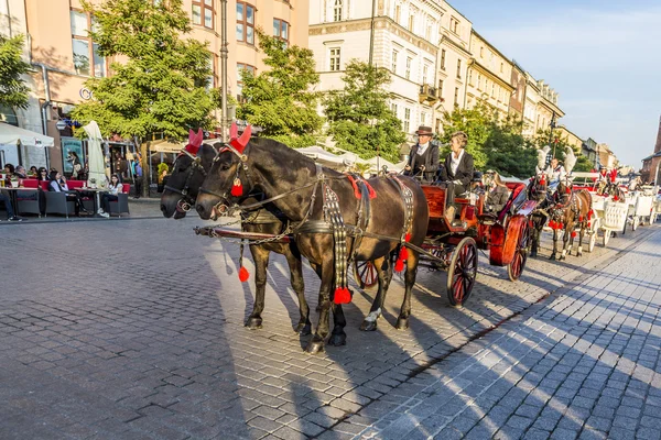 Carruajes de caballos frente a la iglesia Mariacki en la plaza principal de Kr — Foto de Stock