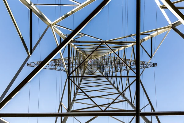 Alta tensão postes de eletricidade contra o céu azul e nuvem — Fotografia de Stock
