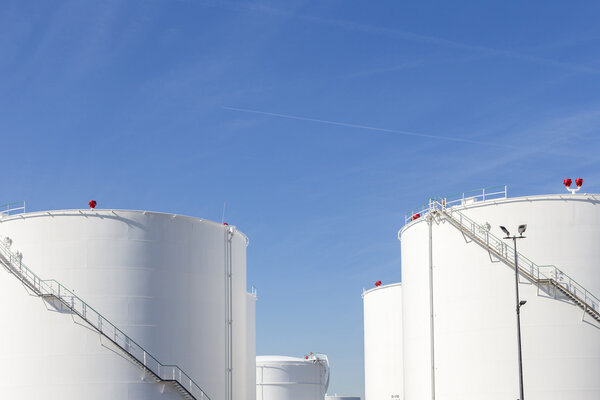 white tanks in tank farm with iron staircase  