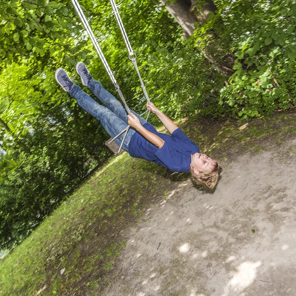 Young child plays on swing in the outdoor playground — Stock Photo, Image