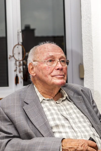 Glimlachend senior man zit bij de leerstoel — Stockfoto