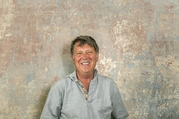 Portrait of senior man in front of grungy old wall — Stock Photo, Image