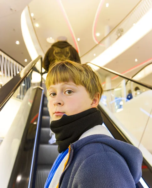 Barn på moving trappa ser själv säker och leenden — Stockfoto
