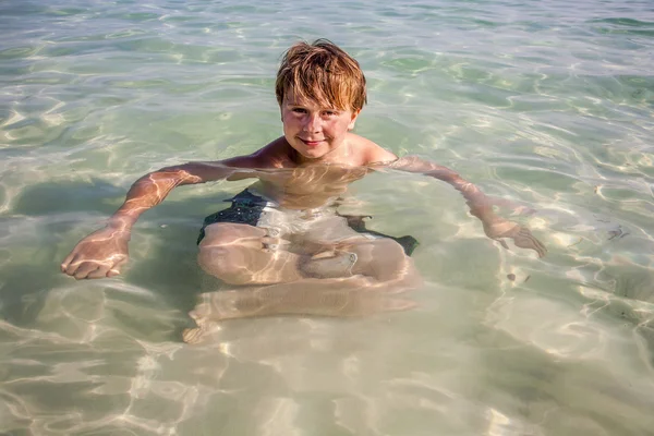 Menino bonito gosta de se sentar no oceano — Fotografia de Stock