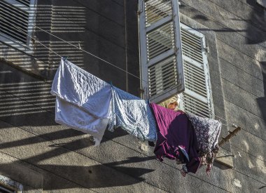 woman with scarf pegs out the washing on a washing line in front
