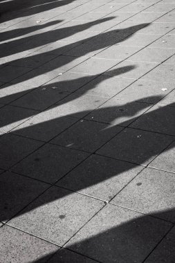 Şehir caddesini geçmek için bekleyen insanların gölgesi