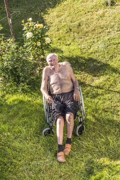 Homem idoso relaxa na cadeira de rodas — Fotografia de Stock