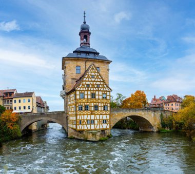 Almanya 'daki Bamberg şehri. Arka planda mavi bulutlu gökyüzü olan belediye binası. Mimarlık ve Avrupa 'da seyahat. Önplanda akan nehir.