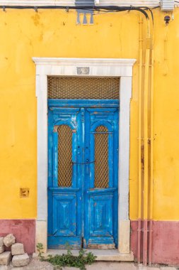 Portekiz 'in Loule şehrinde sarı ve kırmızı boyalı duvarda pittoresk manzaralı eski çürük tarihi ahşap kapı.