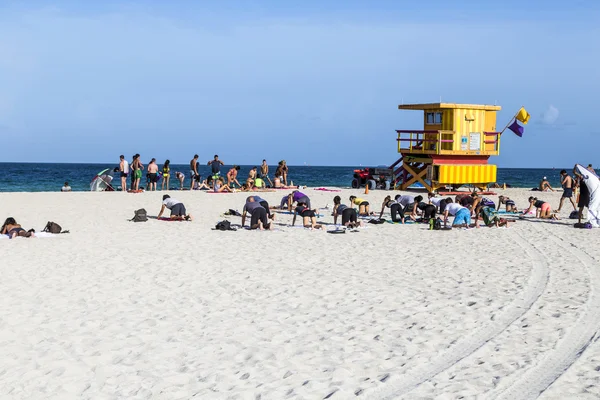 People do fitness training at the beach next to a lifeguard towe — 图库照片