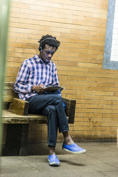 Teenager listens to music while waiting at subway statio — Stok fotoğraf