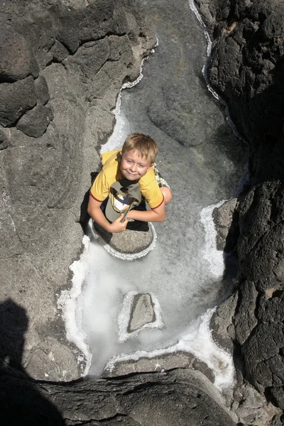 Schattige lachende jongen heeft plezier in de zoute rotsen — Stockfoto