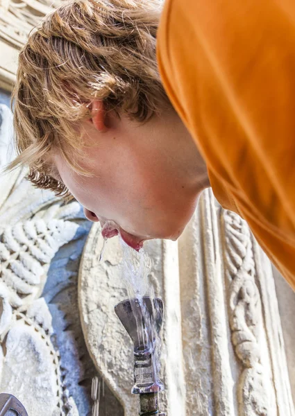 Le garçon boit de l'eau sur une fontaine publique — Photo