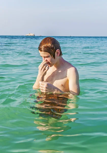 海で泳いでいるくしゃみをする少年 — ストック写真