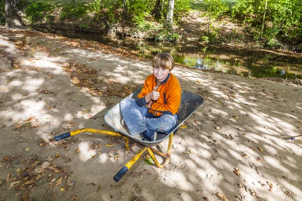 Child sits in the wheel barrow and relaxes — Stock Photo, Image