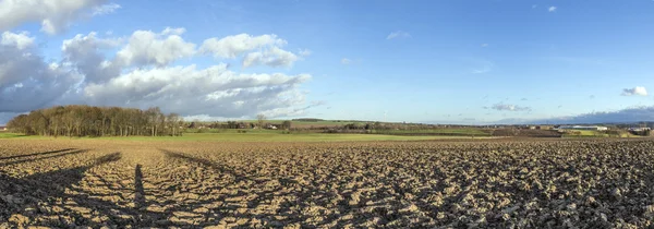 Landdistrikterne landskab med pløjet marker og blå himmel - Stock-foto