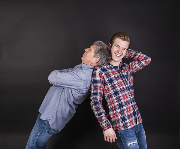 Father and son lean on back to back — Stock Photo, Image