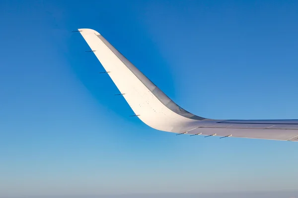 Vleugel van vliegtuigen onder de blauwe hemel — Stockfoto