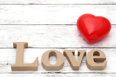 Kırmızı kalp süslemesi yaşlanmış beyaz ahşap bir masada 