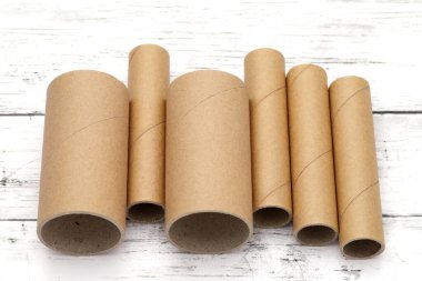 Beyaz ahşap bir masanın üzerindeki karton silindirler.   