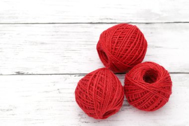 Beyaz ahşap masada kırmızı iplikçikler.