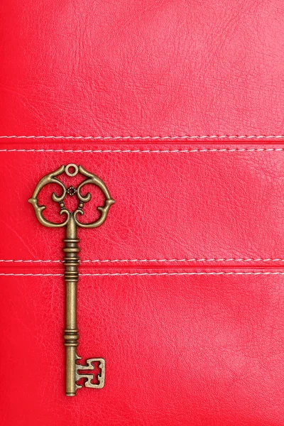 Antique key on red leather — Stock Photo, Image