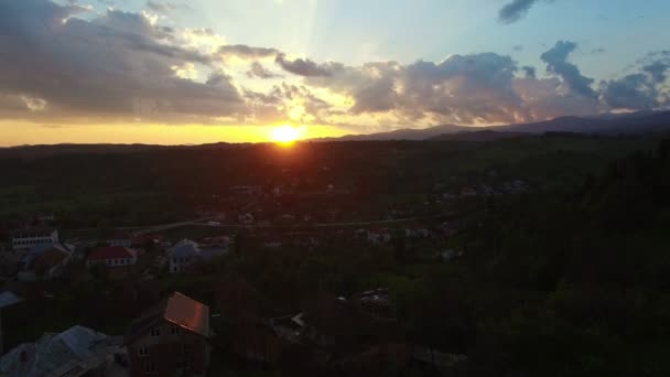 Політ над зеленими пагорбами і селом, красивий схід сонця — стокове відео