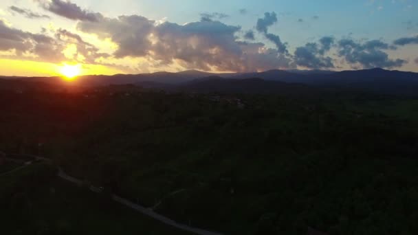 녹색 언덕 및 일몰에 산맥에 대 한 마을 비행 — 비디오