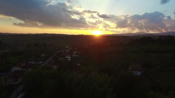 Flight over green hills and village, beautiful sunset — Stock Video