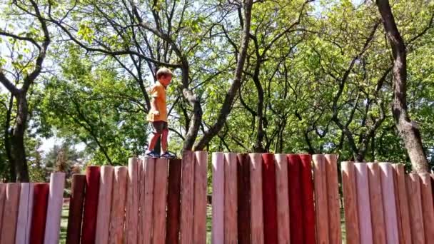 Jongetje lopen op houten veiligheidsschakelingen — Stockvideo