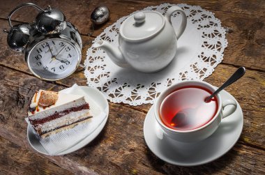 Saat beş çayı. Pasta, çalar saat ve çay süzgeci olan eski ahşap bir masada beyaz çay seti. Alice Harikalar Diyarında tarzında