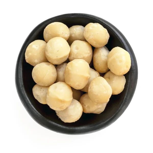 Macadamia-Nüsse in schwarzer Schüssel über Kopf isoliert — Stockfoto