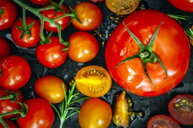Domateslerin çeşitliliği, üst görünüm, siyahın üstünde. Biftek domates, kiraz domatesleri, roma ve kiraz, bütün ve kes.