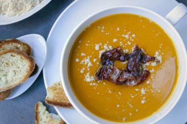 Jambonlu balkabağı çorbası, parmesan peyniri ve kabuklu ekmek. Üst manzara, beyaz kasede..